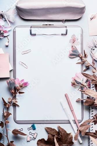 Modern desktop background with gray clipboard, blank paper sheet , office accessories and flowers. Top view, flat lay.  Instagram style