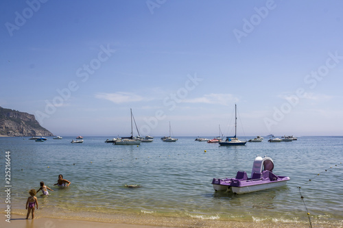 SESIMBRA, PORTUGAL - CIRCA SEPTEMBER, 2018: Scenic beach with recreation boats and people on water photo