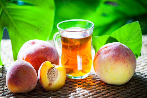Fruits tea made from  peach, organic tea , fresh peach fruits whole and half on a natural tropical background.