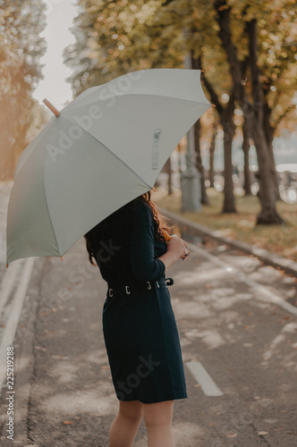 Woman with umbrella in the bright autumn yellow park