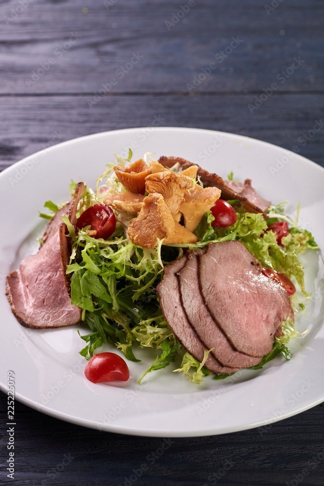 A hearty nice salad for the festive table. Slices of salted meat, bacon, beef, veal, pork from oven, meat sausage, ham. Appetizer from greenery, arugula, mushrooms chanterelles and cherry tomatoes. A hearty nice salad for the festive table. Slices of salted meat, bacon, beef, veal, pork from oven, meat sausage, ham. Appetizer from greenery, arugula, mushrooms chanterelles and cherry tomatoes.