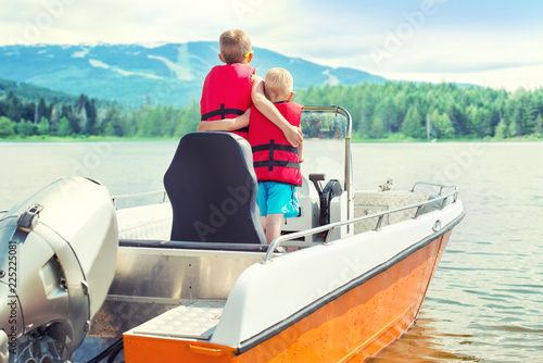 Two brothers swim on a motor boat on the lake. 
