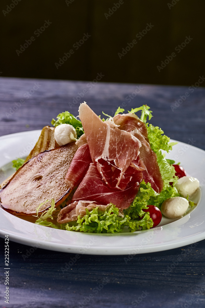Expensive Italian, Spanish, French salad for festive table. Snack from pear, mozzarella, jamon, greens, lettuce, sauce. Cuisine of France, Spain, Italy. Photo of food for menu, cookbook, culinary blog Expensive Italian, Spanish, French salad for festive table. Snack from pear, mozzarella, jamon, greens, lettuce, sauce. Cuisine of France, Spain, Italy. Photo of food for menu, cookbook, culinary blog