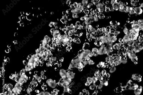Levitating water drops. Stream of water hover on black background. Spa concept.