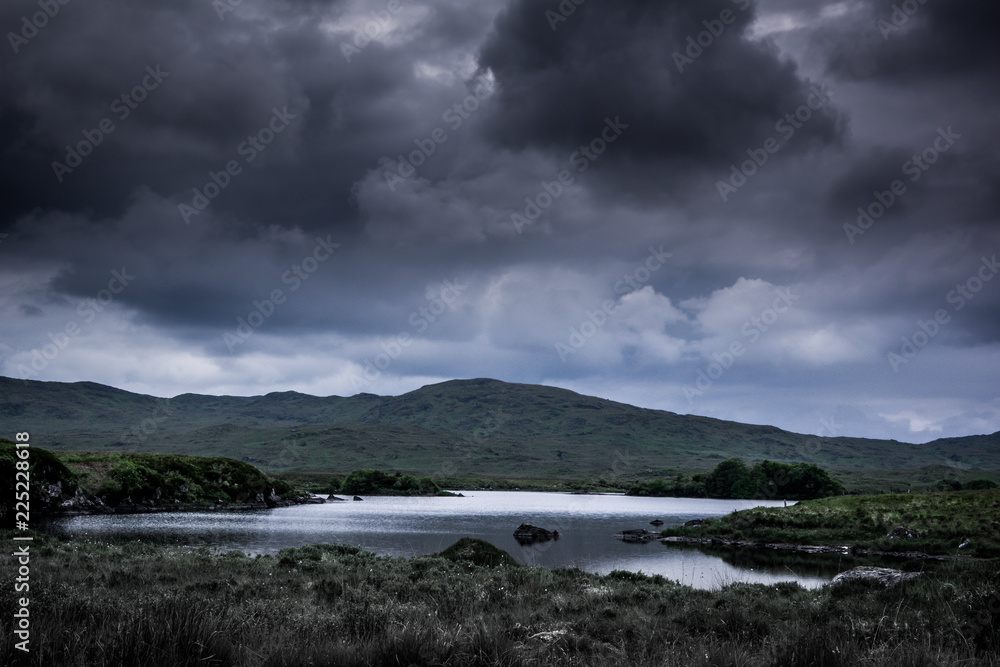 Landscape view of blue lake and dark cloudy sky above.Ireland.