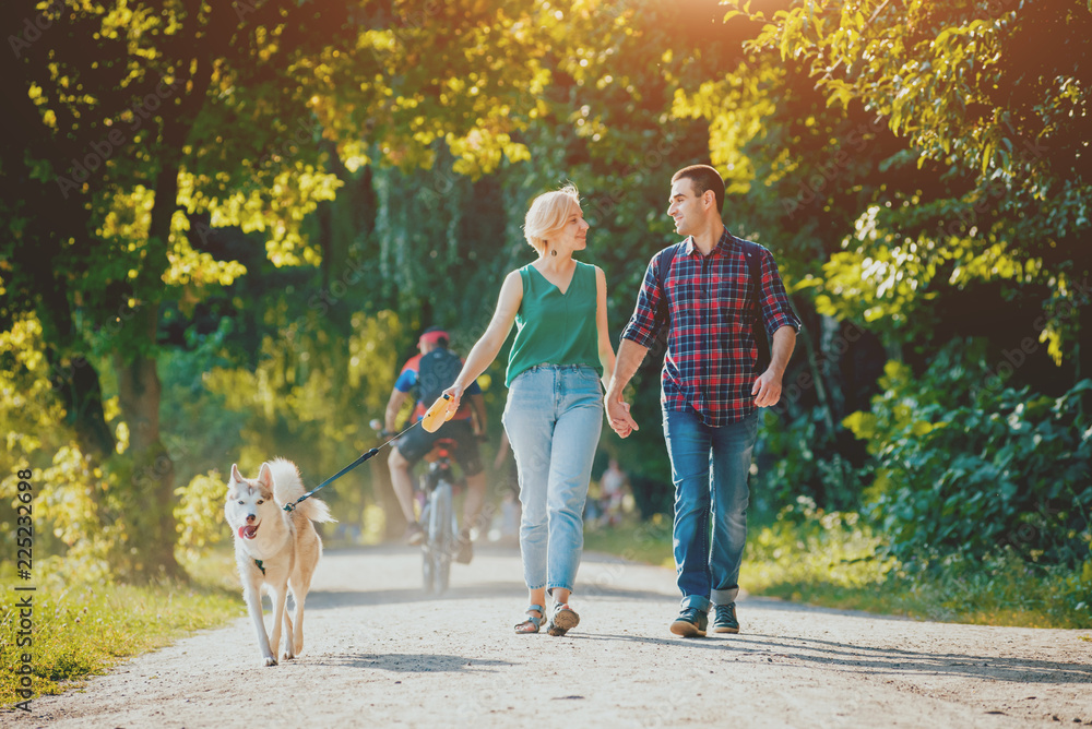 Dog with owners spend a day at the park. Young couple and husky running, playing and having fun. Dog with owners spend a day at the park. Young couple and husky running, playing and having fun.