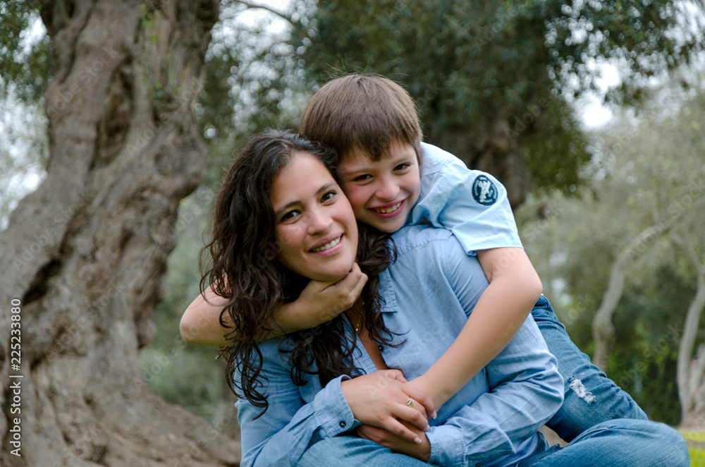 Child hugging his mother smiling on an autumn afternoon Child hugging his mother smiling on an autumn afternoon