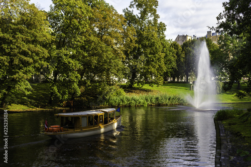 A boat on the lake with a fountain in the park in the autumn .