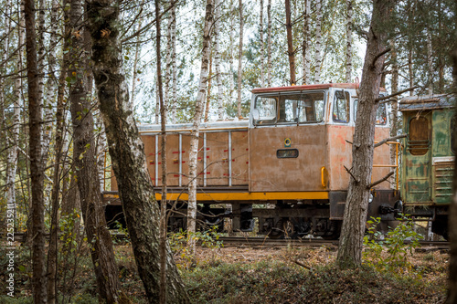 Narrow gauge railway leading through a forest. Narrow railroad riding through colorful birch alley in autumn colors. Authentic Soviet time train with impressive locomotive. 