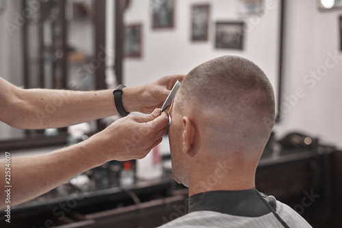 Haircut and hair styling in barbershop. Hair Care. Men's style and lifestyle. Barber brings a haircut and beard to his client. © callisto