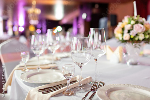 Round table at a luxury wedding reception. Beautiful flowers on the table. Serving dishes, glass glasses, waiters work,