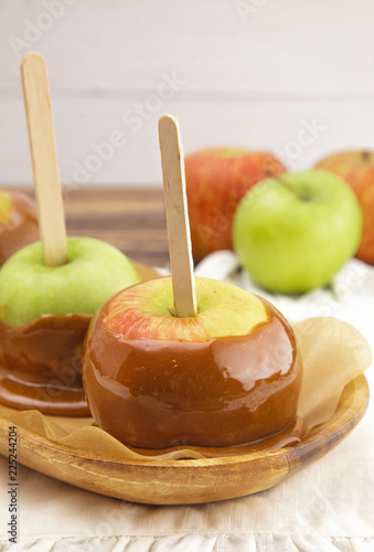 Three Hand Dipped Homemade Caramel Apples on a White Tablecloth