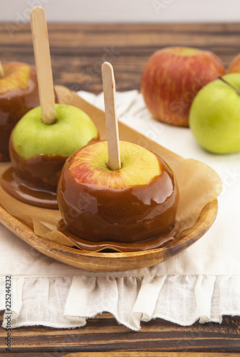 Three Hand Dipped Homemade Caramel Apples on a White Tablecloth