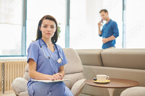 Portrait of female doctor posing in office of modern clinic holding clipboard  copy space
