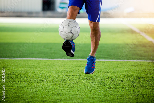 Soccer player jump and shoot ball to goal on artificial turf.