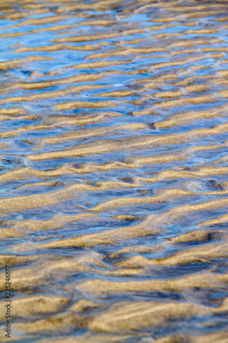 Blue water caught in sand ripples