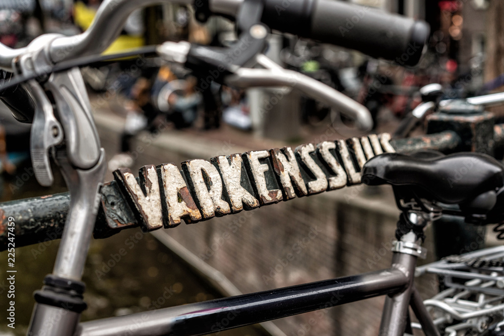 Abgestelltes Fahrrad an Brücke mit antiker Beschriftung in Amsterdam Abgestelltes Fahrrad an Brücke mit antiker Beschriftung in Amsterdam