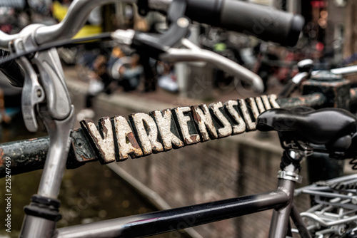 Abgestelltes Fahrrad an Brücke mit antiker Beschriftung in Amsterdam 