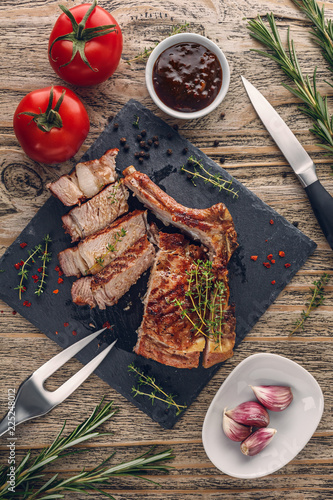 Fotografia Sliced grilled veal chop with vegetables on rustic table