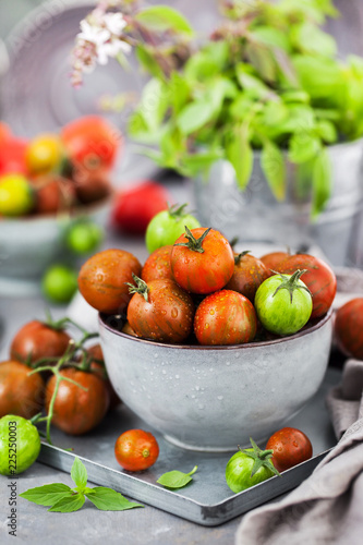 Fresh ripe cherry tomatoes in bowl on gray background