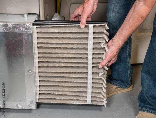 Canvas Print Senior man changing a dirty air filter in a HVAC Furnace