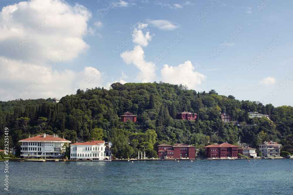 View of historical, old Turkish / Ottoman houses by Bosphorus on Asian side of Istanbul. It is a sunny / cloudy summer day.