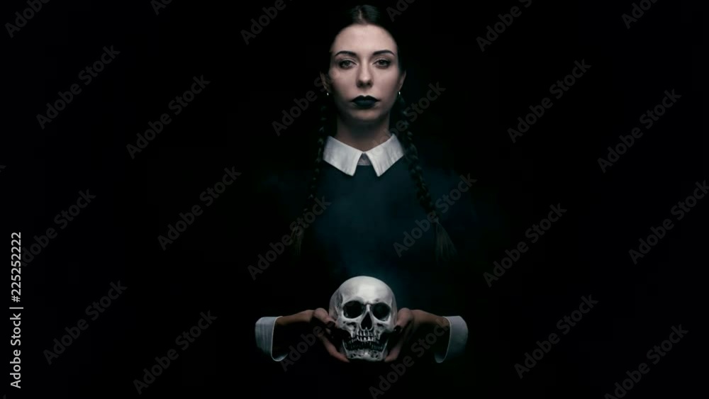 Pale girl with pony tails holding skull on black background, shallow depth of field Pale girl with pony tails holding skull on black background, shallow depth of field