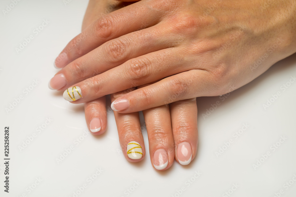 French manicure and nail gel Polish. The decoration of the nail white and gold decor. Top view Close-up photography French manicure and nail gel Polish. The decoration of the nail white and gold decor. Top view Close-up photography