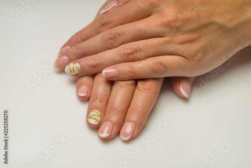 French manicure and nail gel Polish. The decoration of the nail white and gold decor. Top view Close-up photography