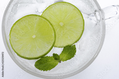 Glass of lemonade with  green lemon slices and mint. © Kasamsak