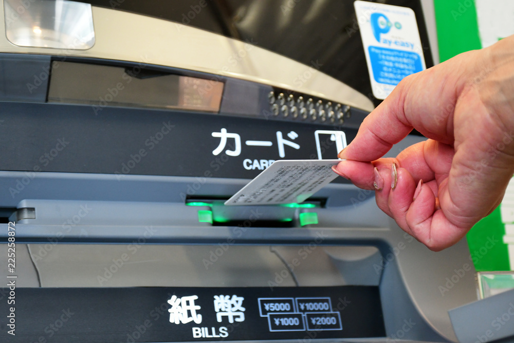a hand having credit card for withdrawing money at ATM
