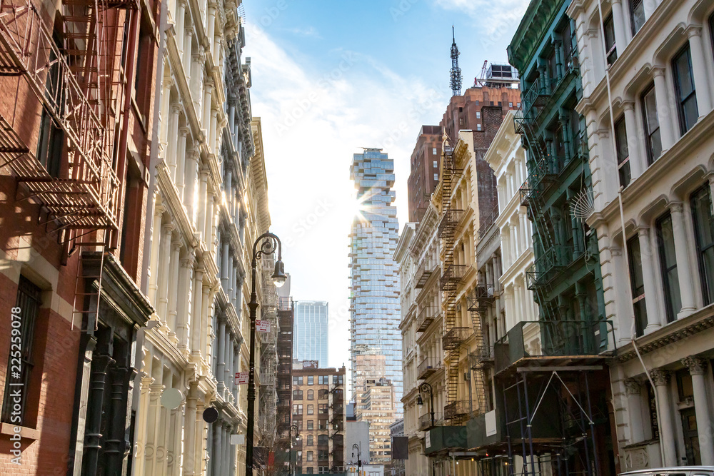 Fototapeta premium Widok na zabytkowe budynki na skrzyżowaniu ulic Greene i Canal w SoHo Manhattan, Nowy Jork z promieniami słońca świecącymi w tle