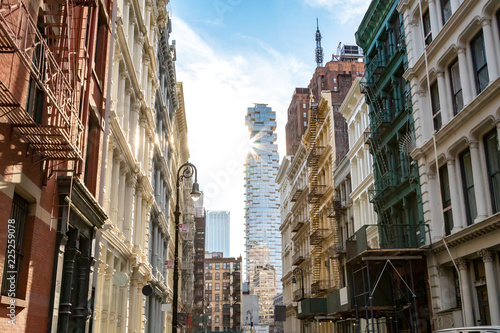 View of the historic buildings at the intersection of Greene and Canal Streets in SoHo Manhattan, New York City with sunlight shining in the background © deberarr