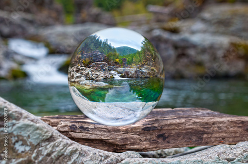 Crystal glass ball sphere reveals nature landscape with macro view