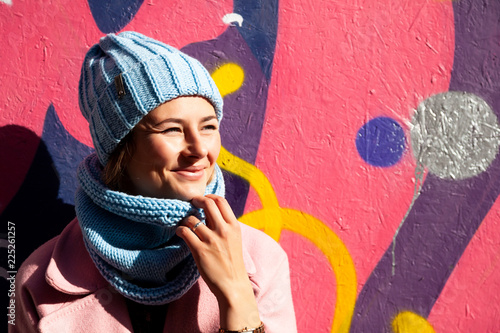 Portrait female student on bright background. Beautiful modern urban young woman wearing blue knitting hat  smile, look away and engoy summer sunny day. photo