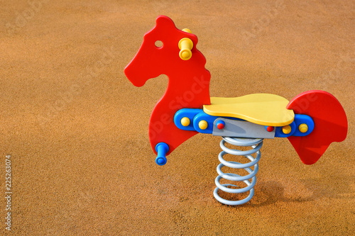 Colorful swing in shape of horse for children in playground on rubber flooring background with copy space for text. photo