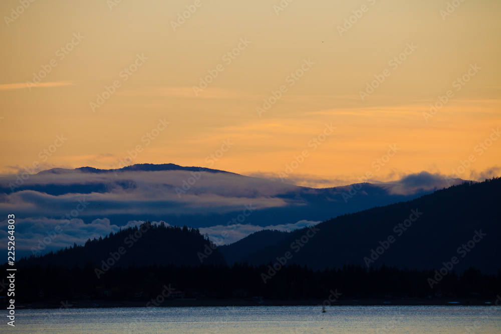 Silhouetted hills around Shuswap Lake and colorful orange sky, British Columbia, Canada