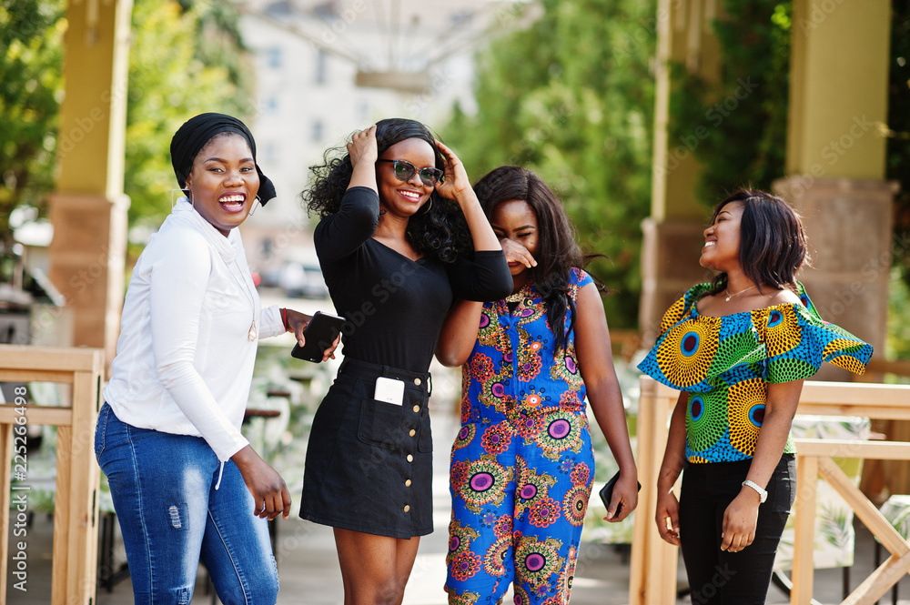 Group of four african american girls posed outdoor against city restaurant summer terrace. Group of four african american girls posed outdoor against city restaurant summer terrace.