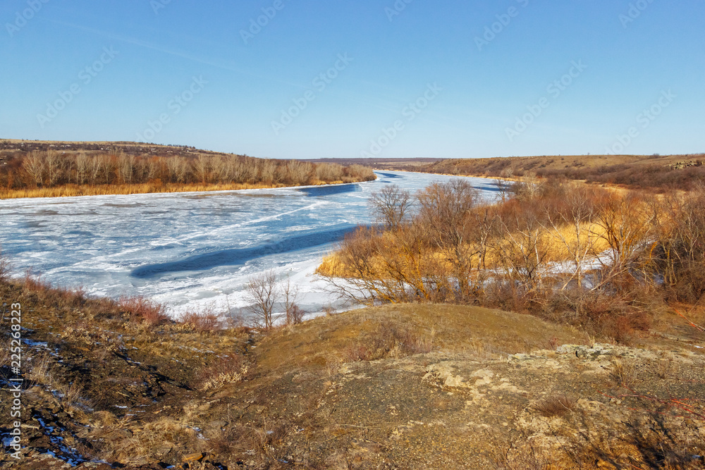 The winter snowless landscape with the frozen river and the forest on the shore. Seversky Donets river, Rostov-on-Don region, Russia