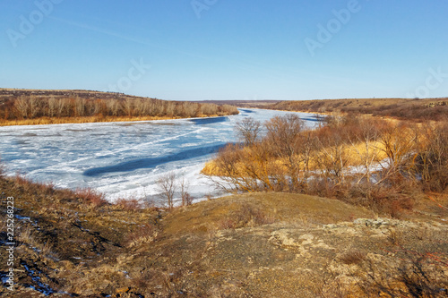 The winter snowless landscape with the frozen river and the forest on the shore. Seversky Donets river  Rostov-on-Don region  Russia