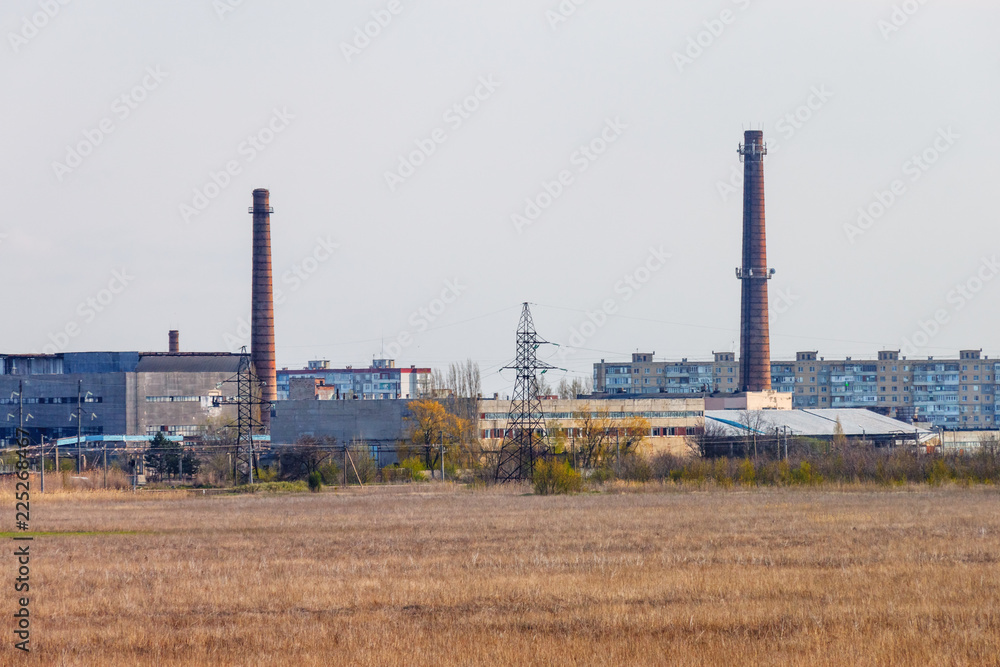 Two industrial brick chimney in the manufacturing area with residential buildings in the background