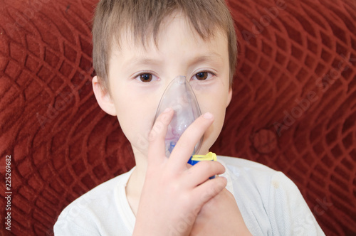 sick boy in nebulizer mask making inhalation, respiratory procedure by pneumonia or cough for child,  inhaler, compressor nebulizer,  nebules machine for health care. Kid catch cold photo