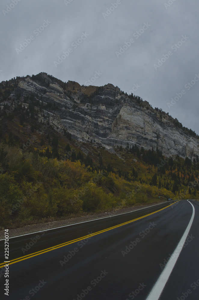 Fototapeta premium The wet road on mountain side under the rocky granite peaks in utah. 
