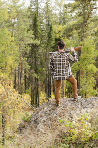 Wallpaper Mural A hunter man staying in a forest and holding a gun on his shoulder Torontodigital.ca