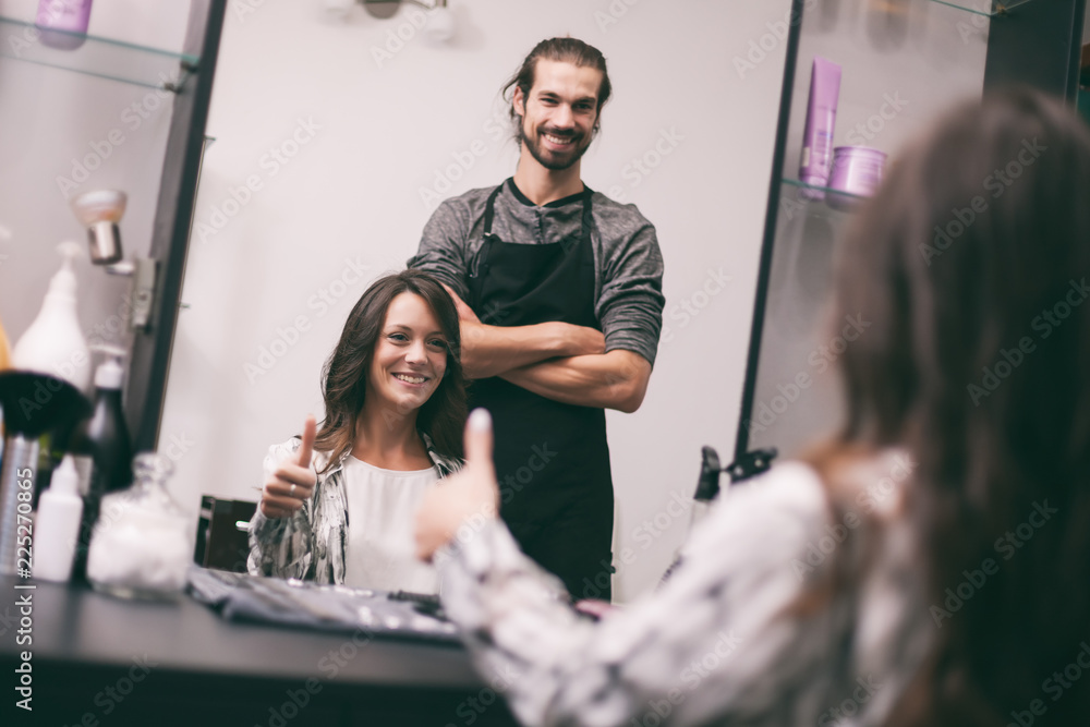 Obraz premium Young woman getting new hairstyle at professional hair styling saloon. She is very satisfied.