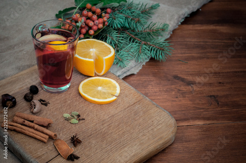 Angle view mulled wine with citrus, cinnamon, cardamon and anise spices and fir. Christmas cozy still life on wooden rustic background.