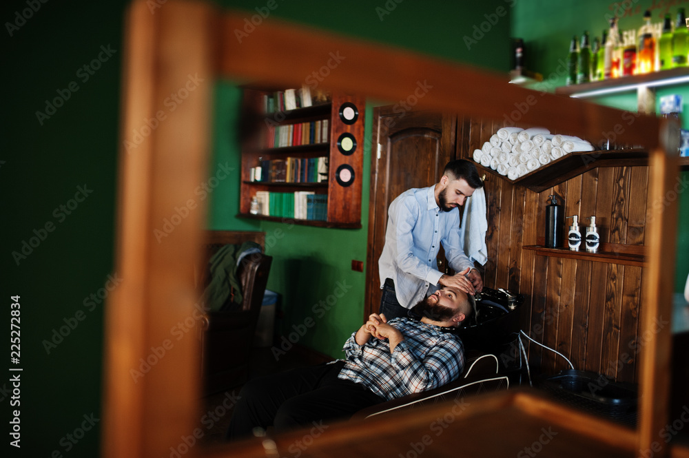 Handsome bearded man at the barbershop, barber at work. Washing head.