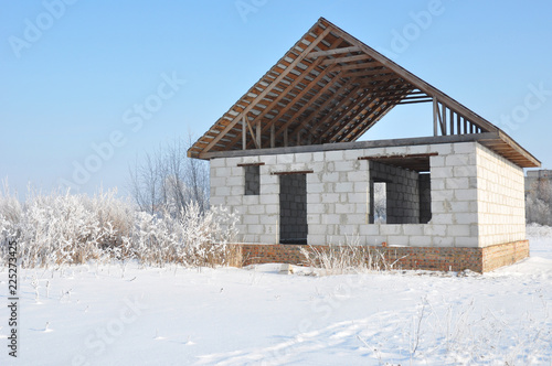 House construction in winter. Unfinished home roofing metal tiles construction. Roofing Construction in Winter.