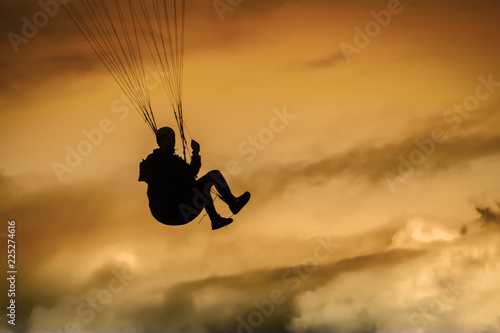silhouette of a man paragliding at sunset
