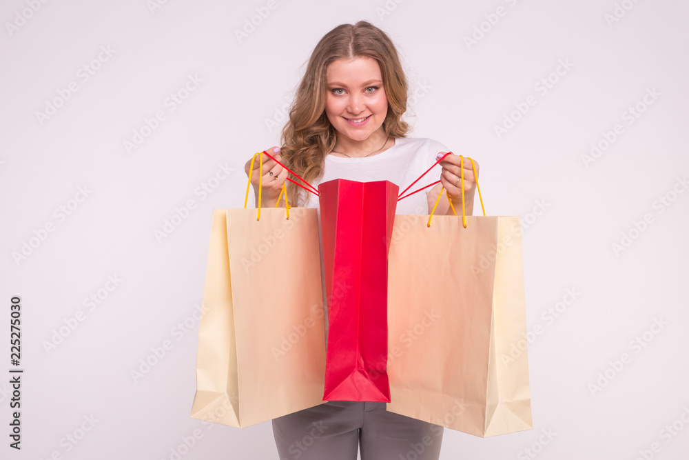 Happy beautiful caucasian woman peeking in shopping bags on white background